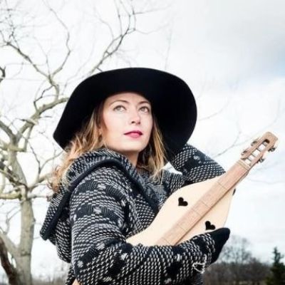 Irene Molloy posing for a photoshoot by carrying a musical instrument, Hora 4 Dulcimer.